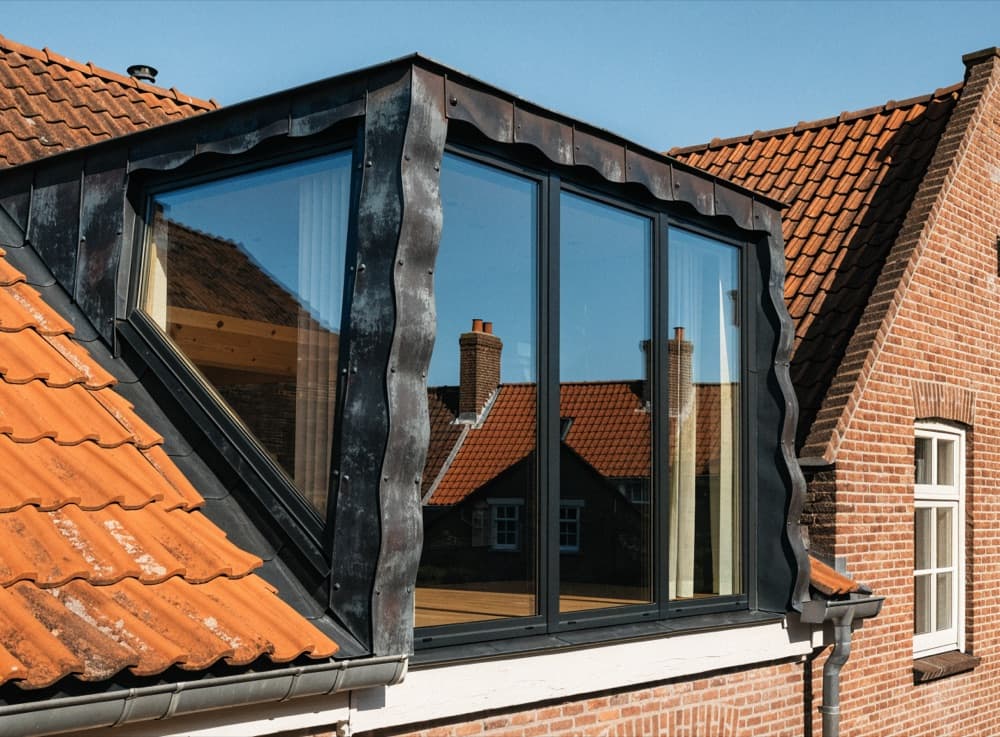 Moderne dakkapel met donkere zinkbekleding en grote ramen op een achterdakvlak