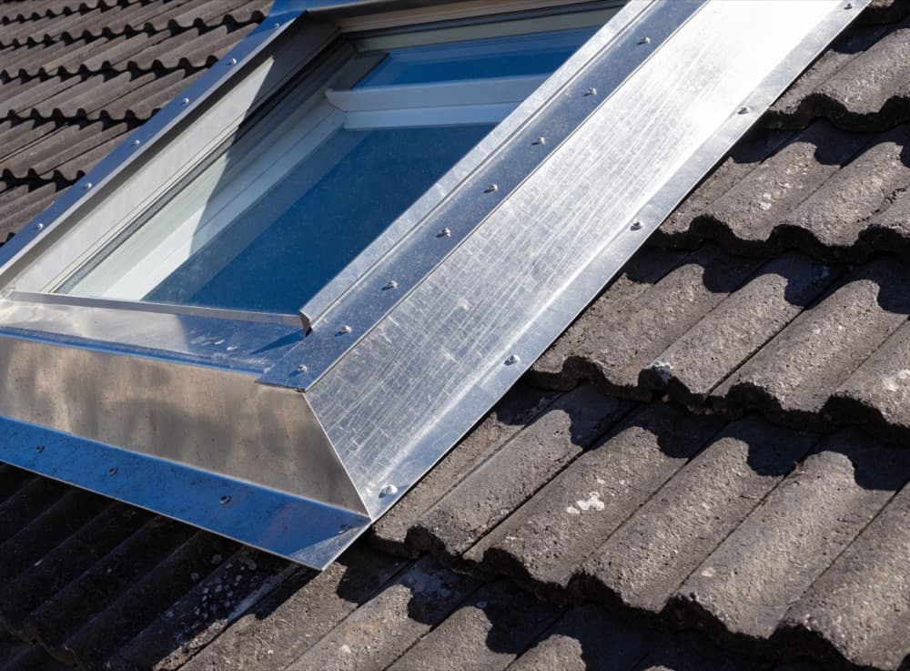 Detail van de aansluiting tussen het gootstuk van een dakraam en de dakpannen