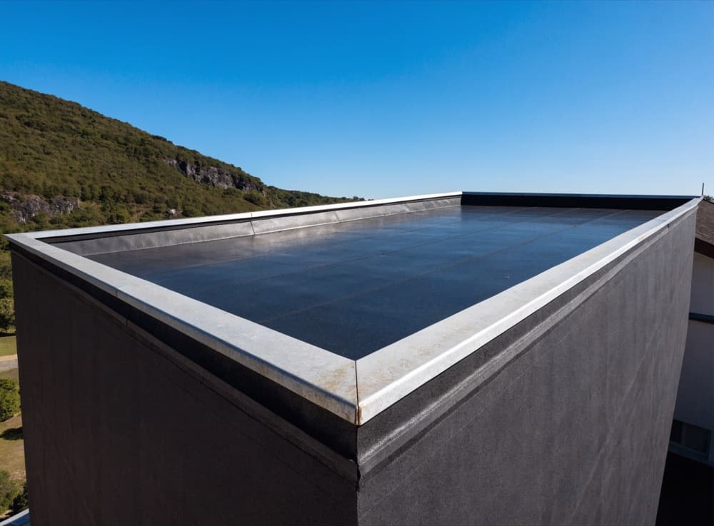 Afgewerkt plat dak van een aanbouw met een lage dakrand en metalen afdekkap